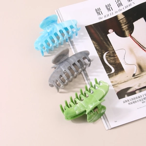 Three large marble-textured acetate hair claws in blue, grey, and green for women