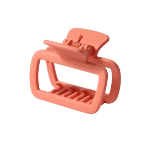 Close-up of coral pink square hair claw clip with matte finish and metal spring