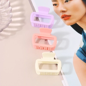 Matte square hair claw clips in pastel purple, peach and cream on a fashion magazine
