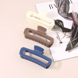 Large matte rectangular claw clips in cream, brown, and navy blue set on a magazine