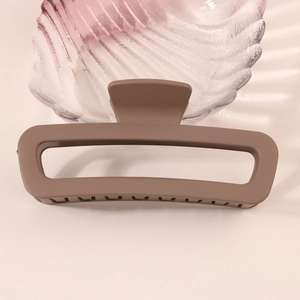 Close-up of a large coffee brown matte hollow rectangle hair claw clip on a tray