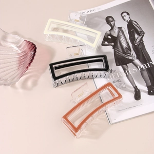 Detailed view of large rectangular hollow hair claws in ivory, black, and caramel brown colors