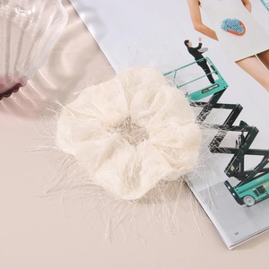 Detailed view of an ivory white feather scrunchie made of light mesh fabric for buns