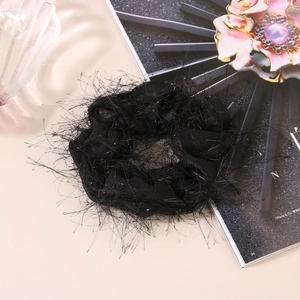 Detail shot of a black gauzy scrunchie with feather texture on a luxury magazine