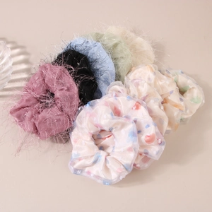 Mix of fluffy plush and colorful polka dot organza scrunchies on beige background