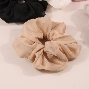 Gros plan sur un grand chouchou en organza plissé doré champagne à texture moelleuse
