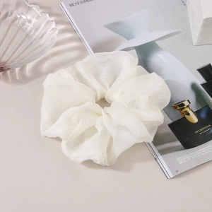 Gros plan d'un grand chouchou blanc en organza avec texture plissée douce sur la table
