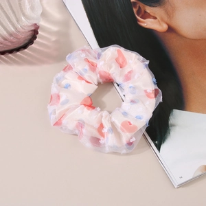 Close-up of cream mesh scrunchie featuring red hearts and blue dots on a stylish magazine
