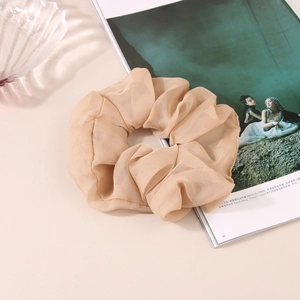 Détail d'un chouchou géant en organza abricot avec texture de tissu doux plissé