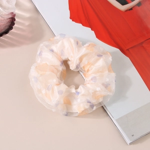 Detail shot of apricot mesh scrunchie with colorful polka dots on a fashion magazine