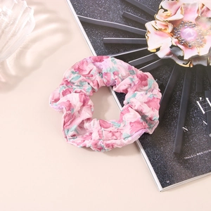Vue détaillée du chouchou rose à fleurs en mousseline avec texture douce à volants