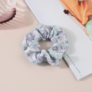 Détail d'un chouchou floral avec motifs bleu clair et vert sur tissu froissé