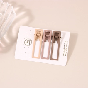 Tre fermagli rettangolari opachi nei colori beige, rosa e marrone su cartoncino