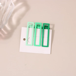 Dettaglio di tre fermagli rettangolari per capelli in tonalità di verde sfumato