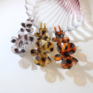 Three elegant butterfly hair claws in purple, amber, and brown tortoise shell resin patterns