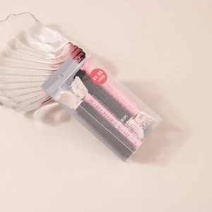 Close-up of pink and black Korean style hair rollers with long clips in clear packaging