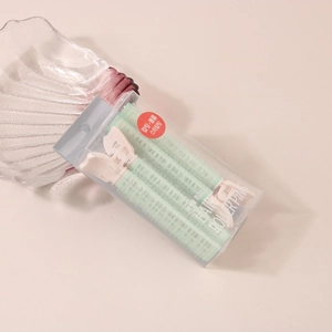 Close-up of hair roller set in mint green with clips in a clear retail display box