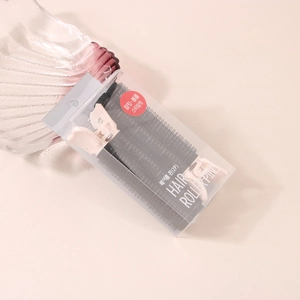 Close-up of pink plastic hair curler clips with black nylon rollers in a 2-pack box
