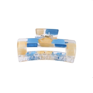 Detailed macro shot of a transparent hair claw clip with blue and gold foil patterns