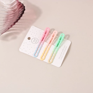 Détail de trois pinces à cheveux ondulées dégradées macaron sur une carte faite main