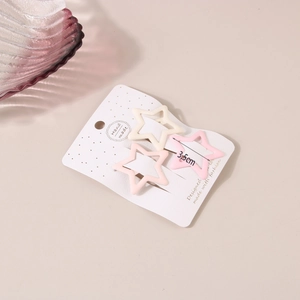 Detailed view of three matte star hair clips in cream and pink on a display card