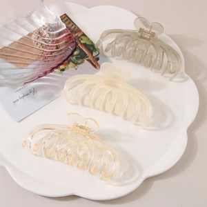 Macro detail of large resin hair claws in heart shape design with gold metal spring