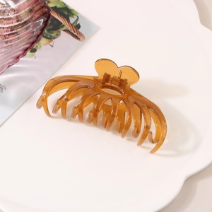 Detail of a large amber hair claw clip with heart-shaped handle on a white tray