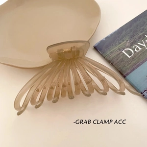 Grande pince à cheveux ambre translucide au design minimaliste posée sur une assiette