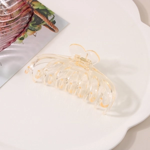 Macro detail of a large champagne butterfly hair claw clip on a white ceramic tray