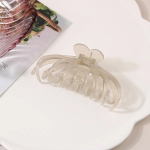 Macro view of a large translucent champagne gray heart hair claw clip with golden spring