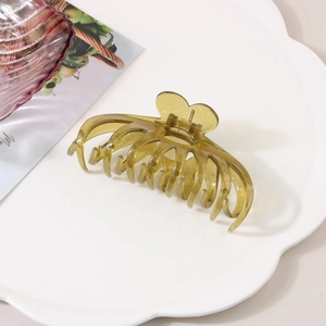 Detail of transparent olive green hair claw clip with strong metal spring on a white tray