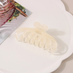 Macro detail of cream-colored translucent hair claw with heart accent on cloud tray