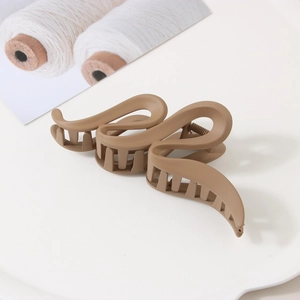 Gros plan sur une grande pince à cheveux mate café au design ondulé élégant