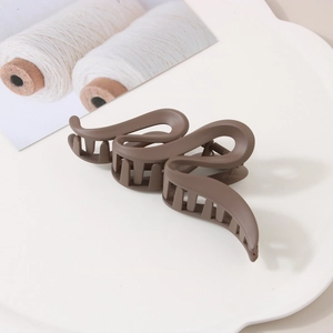 Gros plan sur la pince à cheveux marron chocolat mat sur une assiette en céramique