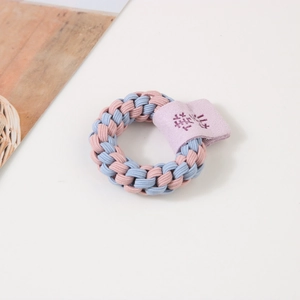 Détail d'un élastique à cheveux tressé rose et bleu avec étiquette en daim mauve