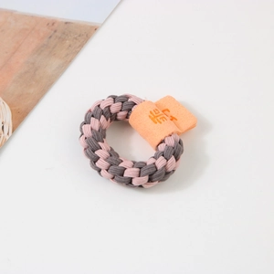 Détail d'un chouchou tressé rose et gris avec une étiquette portant un caractère mignon