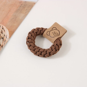 Détail macro d'un élastique tressé marron foncé avec une étiquette décorative d'ours