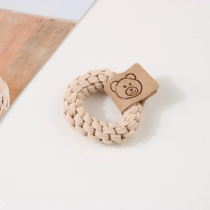 Détail d'un élastique tressé beige avec un écusson en cuir orné d'un ours de dessin animé
