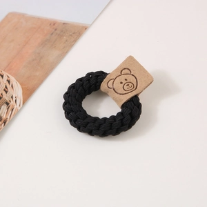 Détail d'élastique à cheveux tressé noir avec patch en cuir motif ours de dessin animé