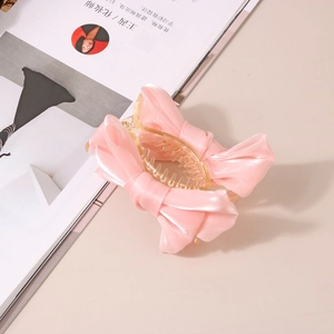 Détail d'une pince à cheveux avec nœud en satin rose sur un fond de magazine