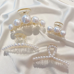 Detailed view of four pearl claw clips set on white silk, showing elegant resin textures