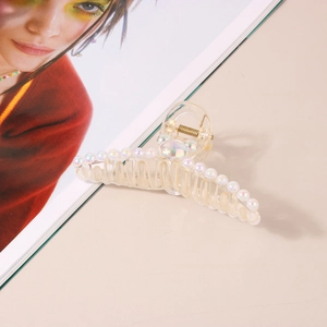 Détail d'une grande pince à cheveux champagne avec perles et design élégant en profil