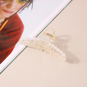 Vue détaillée d'une pince à cheveux fleur transparente avec perles irisées sur fond beige