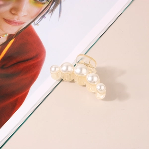 Detailed view of elegant cream pearl hair claw clip set against a fashion magazine