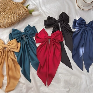 Detailed flat lay of satin bow hair clips in five elegant colors on white bedding