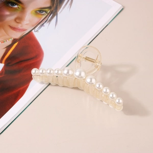 Macro detail of large transparent claw clip featuring elegant white pearl embellishments