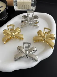 Elegant gold and silver bow metal hair claws displayed on a decorative ceramic tray