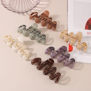 Detailed view of wave-shaped resin hair claws in assorted marbled colors and textures