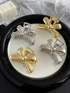 Close-up of polished gold and silver metal bow hair claws arranged on a decorative plate
