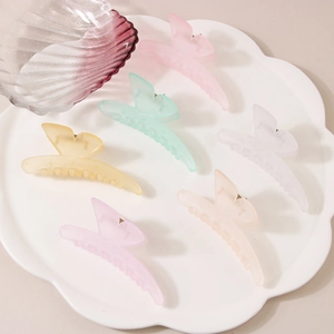 Set of six colorful matte butterfly hair claws in pastel tones on a white tray